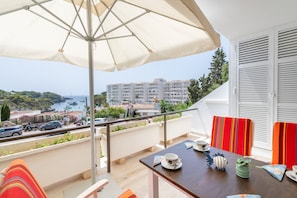 A balcony with a table, chairs, and an umbrella. - "Ola De Mar" with Shared Pool, Wi-Fi, and Air Conditioning (Tourist Tax Included) (Felanitx)