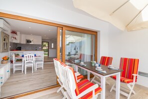 Une cuisine moderne avec des meubles blancs, un four à micro-ondes et un coin repas comprenant des chaises et une table, le tout dans des tons blancs.