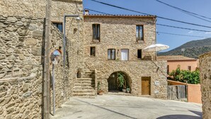 A stone building with a courtyard, a wooden door, and potted plants.