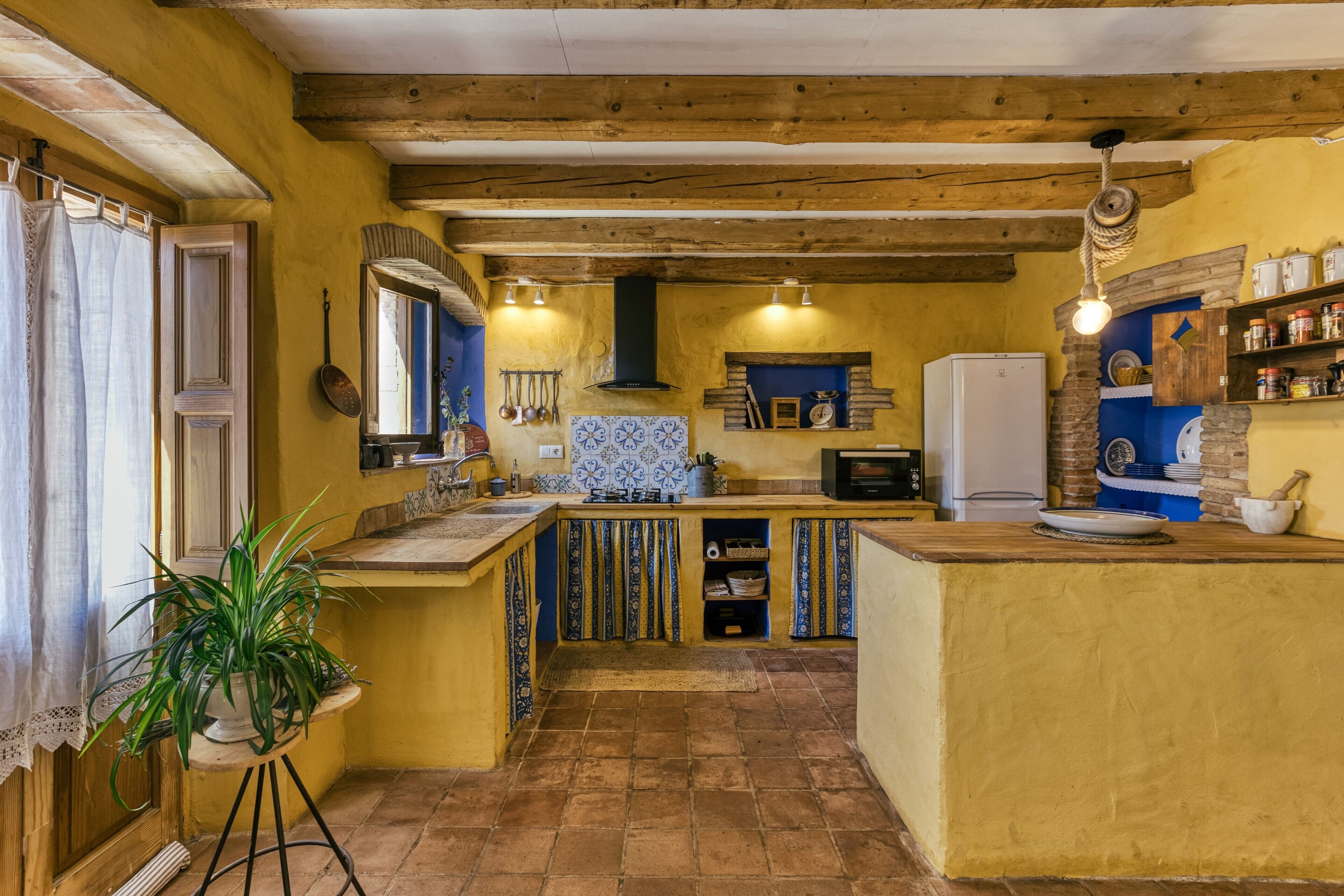 Una cocina con vigas de madera, un salpicadero de azulejos y un refrigerador blanco.