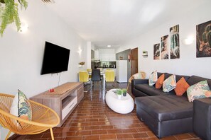 Un salon moderne comprenant un canapé, une table basse, un téléviseur et un coin repas avec des chaises.