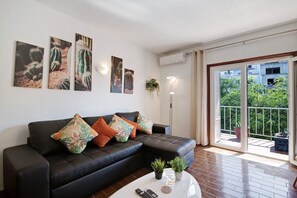 Un salon moderne avec un canapé en cuir noir, une table basse agrémentée d’une plante et des œuvres d’art accrochées au mur.