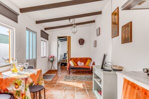 A dining area with a table set for two, a sofa, and a kitchen area with a stove.