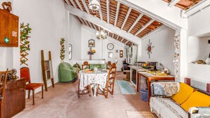 A spacious room with a high ceiling, a dining area with a table and chairs, a sofa, and a kitchen area. - Holiday Home "O Mundo Da Lua - Galinheiro" with Shared Garden and Wi-Fi (São Simão)