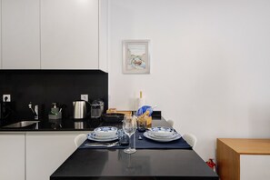 A modern kitchen with a black countertop, white cabinets, and a framed picture on the wall.
