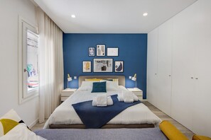 A modern bedroom with a large bed, bedside tables, a wardrobe, and artwork on the wall.