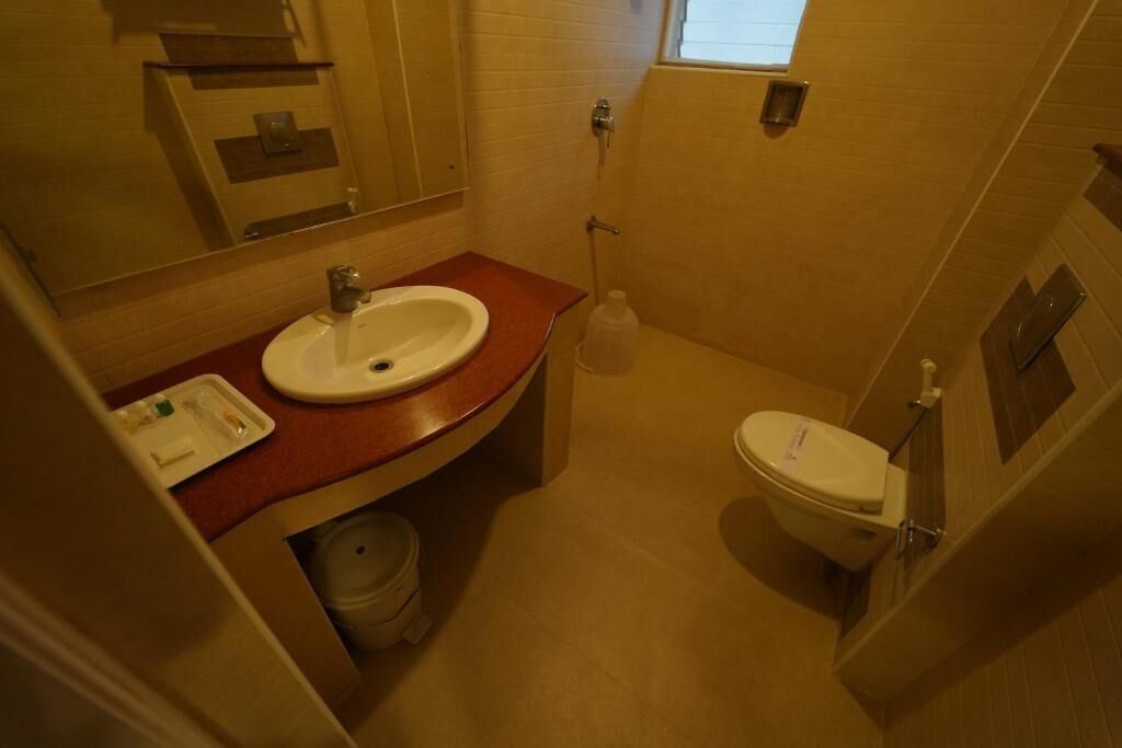 A small bathroom with a white sink, a toilet, and a mirror.