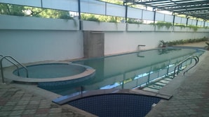 A swimming pool with a glass barrier, a hot tub, and a small pool area. - AAR Royal Residency - Palmyra (Palayankottai)