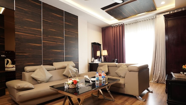 A modern living room with a sofa, a glass coffee table, and a dark wood accent wall. - AAR Royal Residency - Palmyra (Palayankottai)