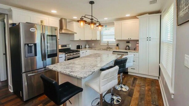 A modern kitchen with a central island, stainless steel appliances, and bar stools.