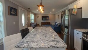 A modern kitchen with a marble countertop, stainless steel appliances, and a dining area with a bench.