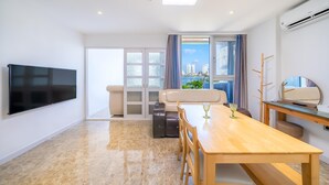 A modern living room with a flat-screen TV, a dining table, and a sofa. - Sokcho Ocean View Pension (Sokcho)