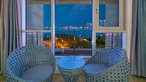 A balcony with two wicker chairs and a small table, overlooking a cityscape at night. - Sokcho Ocean View Pension (Sokcho)