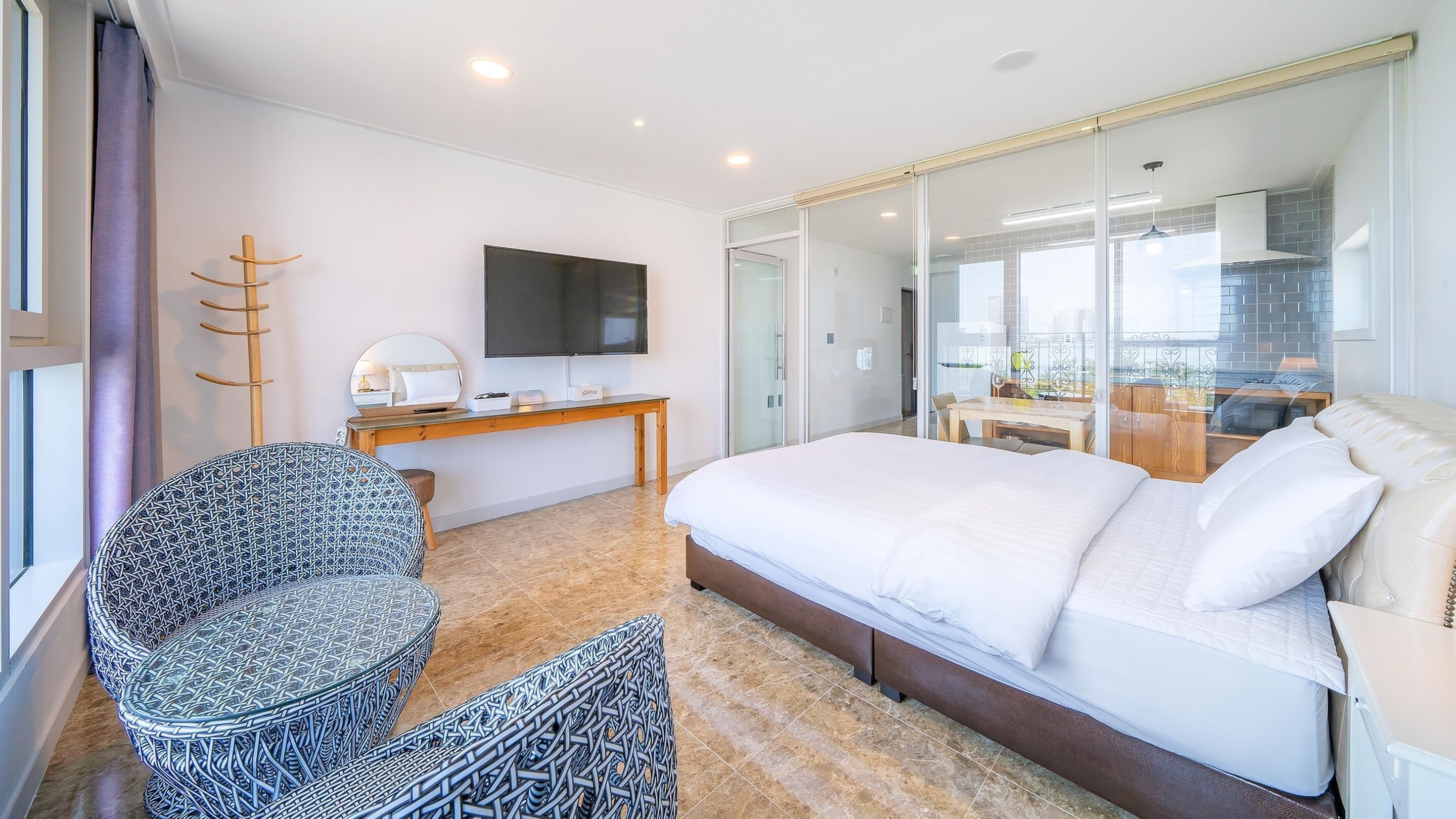 Una habitación de hotel moderna con una cama grande, un escritorio, una silla y un televisor.