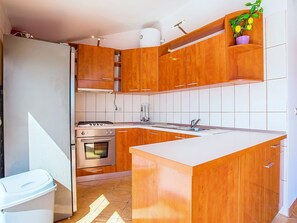 A modern kitchen with wooden cabinets, a built-in oven, and a white countertop. - Villa Jolie Amazing Stone by Interhome (Omiš)