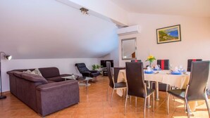 Un salon moderne avec un canapé, des fauteuils et un coin repas comprenant une table dressée pour quatre personnes.