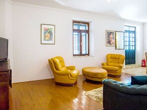 A living room with two yellow armchairs, a small ottoman, a television, and two framed pictures on the wall. - Villa Jolie Amazing Stone by Interhome (Omiš)