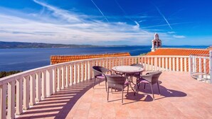 Une terrasse offrant une vue sur la mer et, au loin, on aperçoit un clocher.