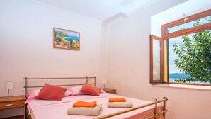 Une chambre à coucher avec un lit, une table de chevet, une fenêtre donnant sur un beau paysage et un tableau accroché au mur.