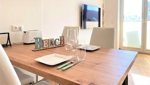 Un coin repas avec une table en bois, un grille-pain, un téléviseur à écran plat et une vue sur l’extérieur.