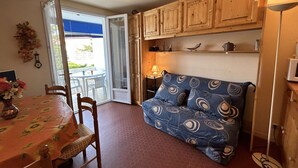 Une pièce chaleureuse comprenant une table à manger, des chaises, un canapé, des meubles en bois et une fenêtre donnant sur l’extérieur.