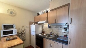 Une cuisine de taille réduite, dotée de meubles en bois, d’un four à micro-ondes, d’un réfrigérateur et d’un évier.