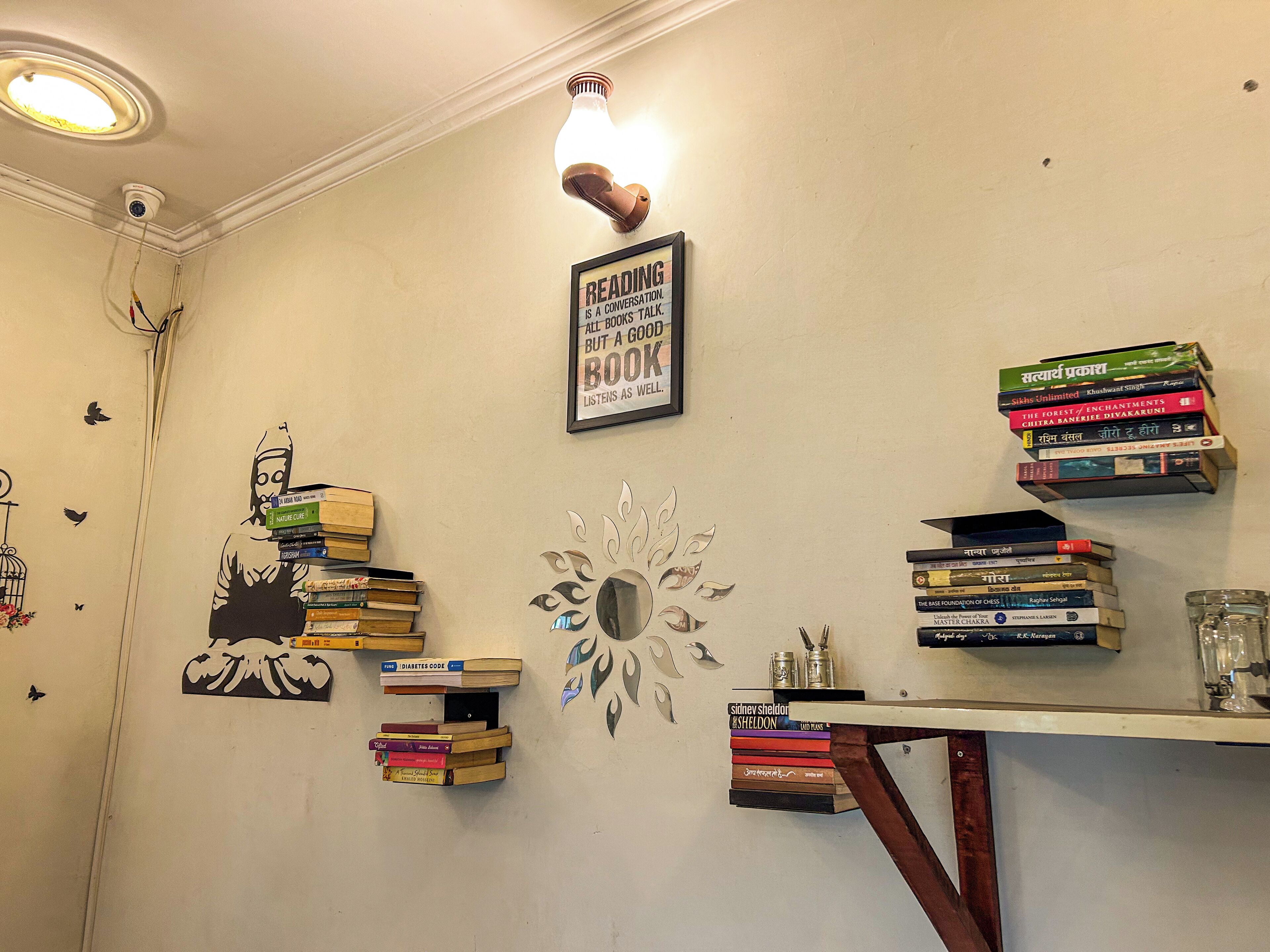 A room with a bookshelf filled with books, a framed quote on the wall, and a decorative wall piece.