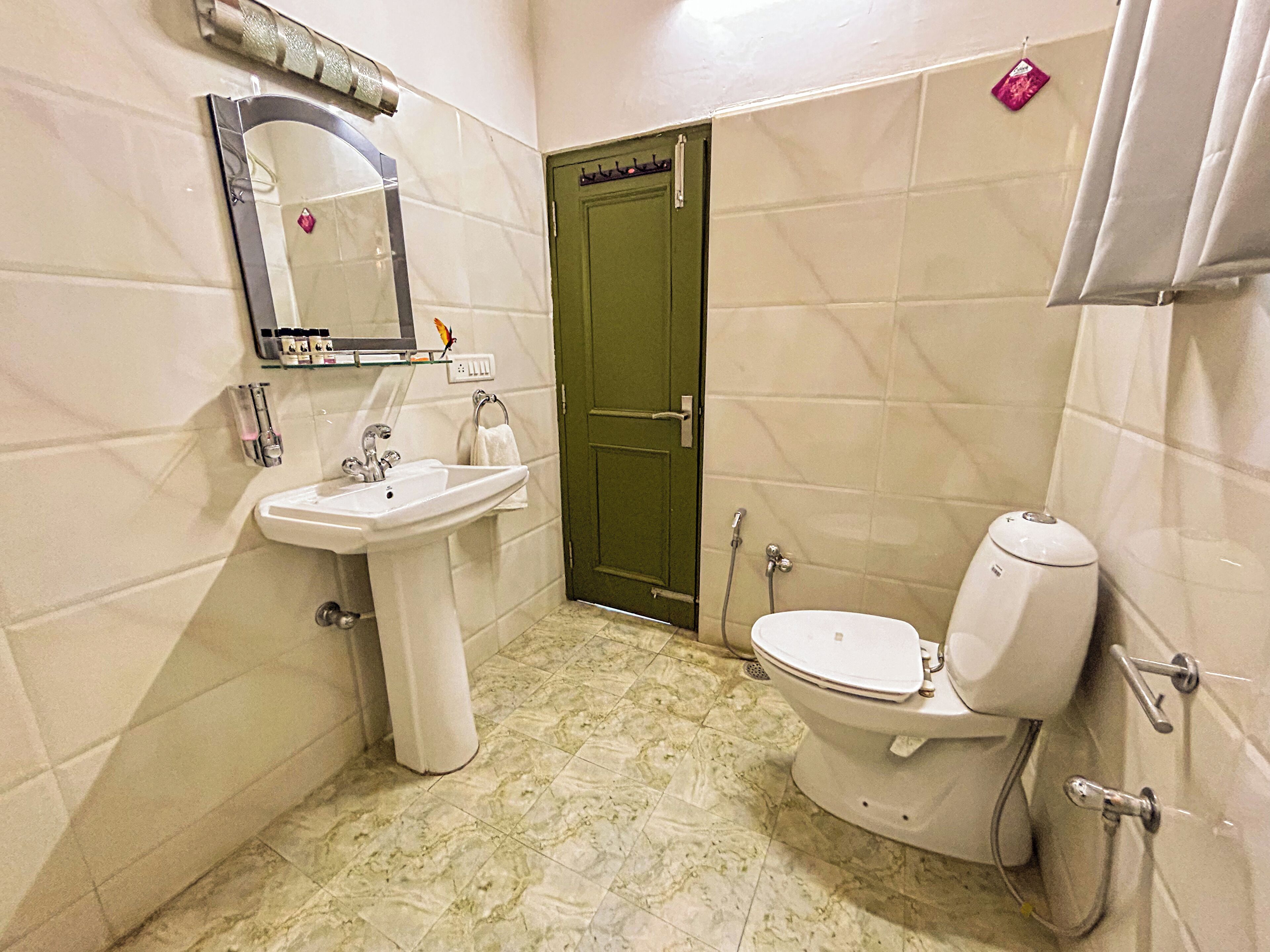 Un baño con lavamanos, inodoro y puerta verde.