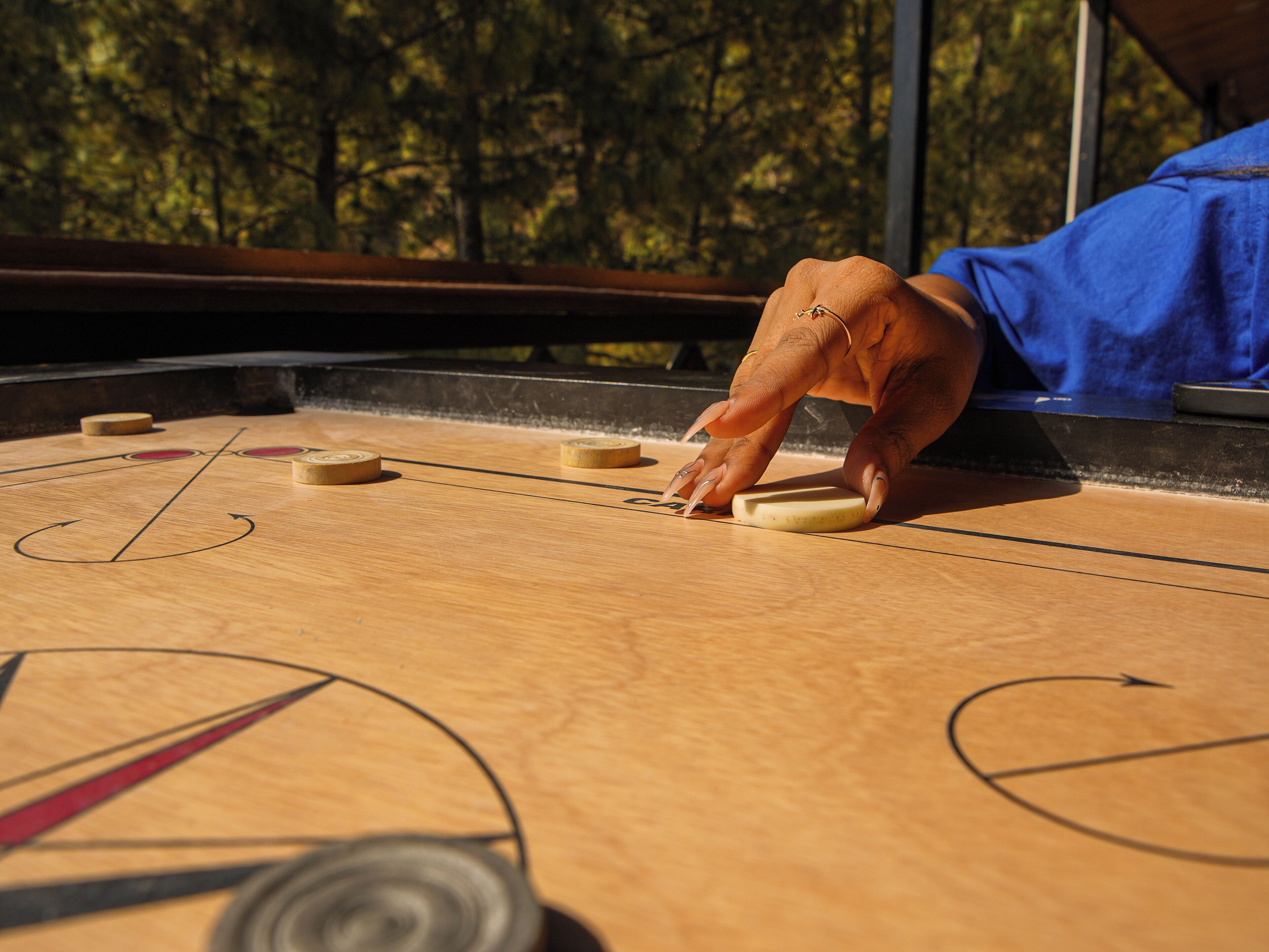 A shuffleboard table with a person's hand holding a puck.