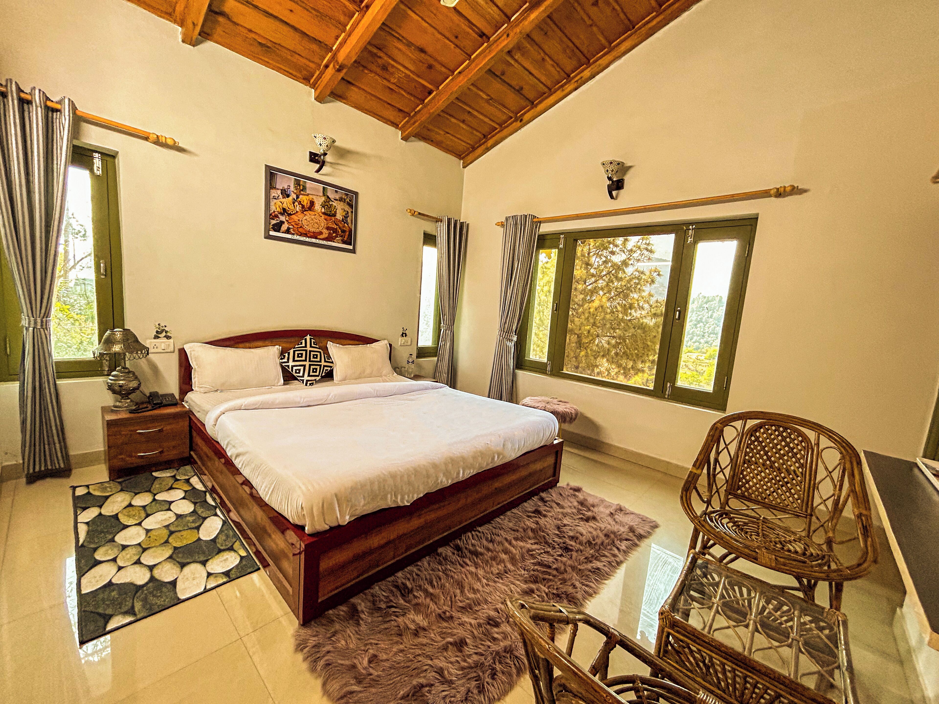 A bedroom with a wooden bed, a fluffy rug, a wicker chair, and a view of trees through the window.