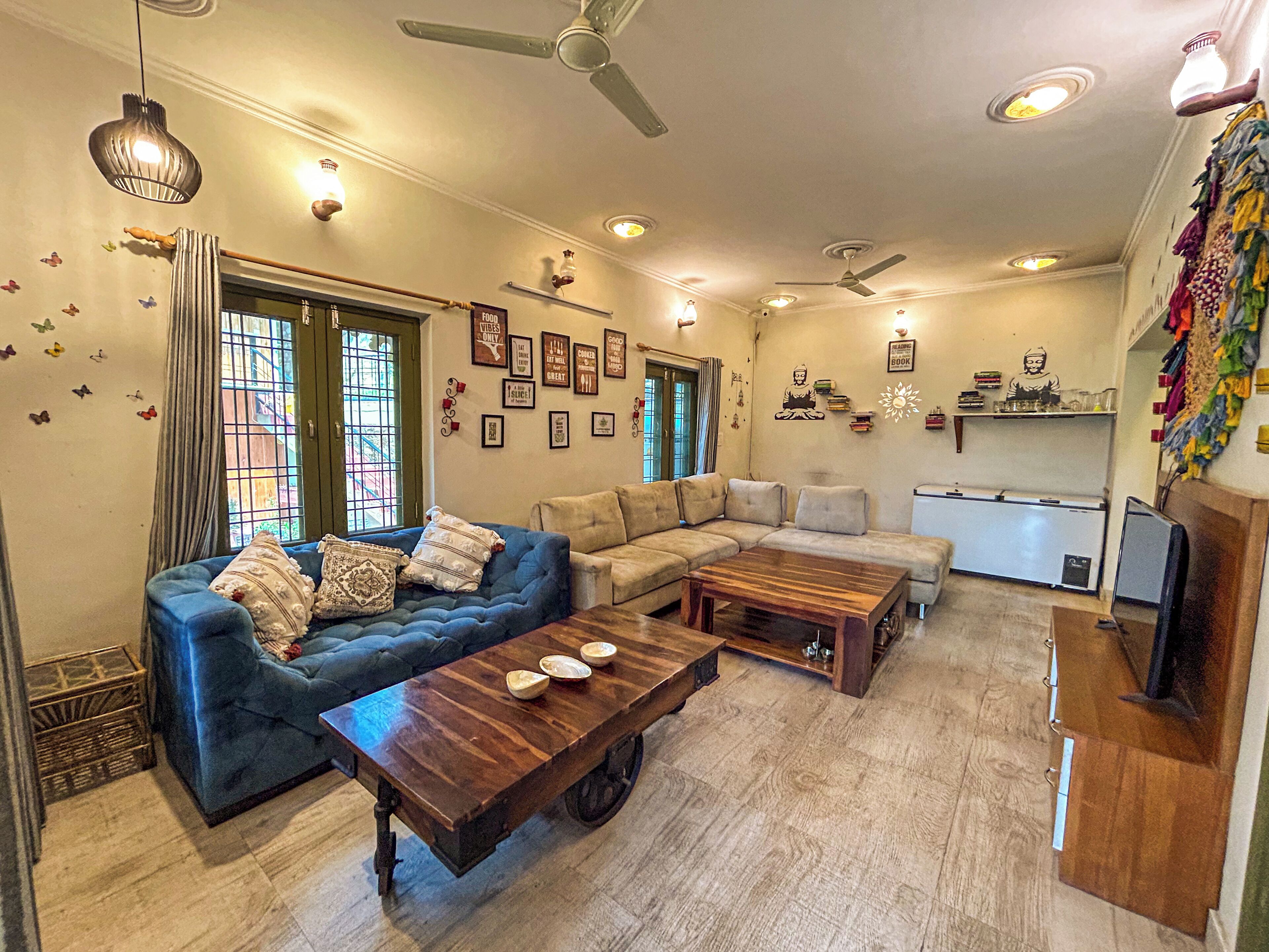 A living room with a blue sofa, a wooden coffee table, a beige sectional sofa, and a white refrigerator.