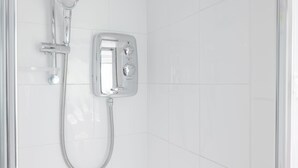 Ducha con cabezal de ducha de mano, panel de control en la pared y un organizador de ducha cromado.