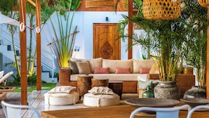 An outdoor seating area with a wooden table, cushioned seating, and wicker furniture.