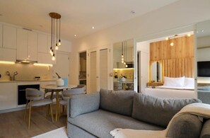 Quarto de hotel moderno com cozinha compacta, área de refeições e uma cama grande.