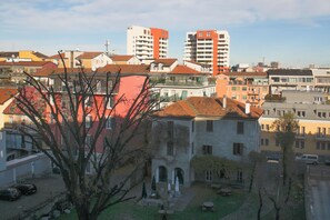 A courtyard with a building featuring a red roof, surrounded by other buildings with various architectural styles. - BnButler - Govone 78 (Milan)