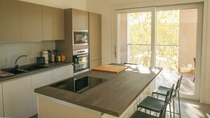 Eine moderne Küche mit Kochinsel, integriertem Backofen und großem Fenster mit Blick auf einen Balkon.