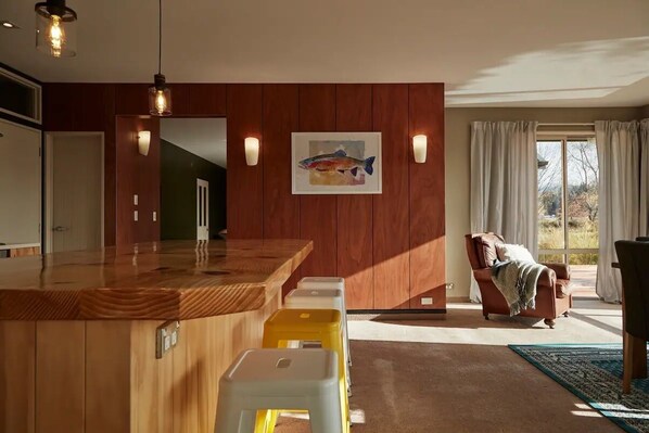A modern kitchen with wooden cabinetry, a central island, and a painting of a fish on the wall. - Mountain View Abode - Spectacular Views In Twizel (Twizel)