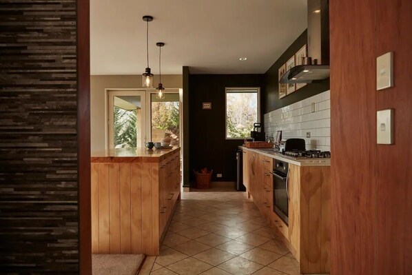A modern kitchen with wooden cabinetry, a central island, and pendant lighting.