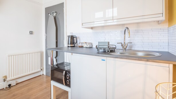 A modern kitchen with white cabinets, a stainless steel sink, and a built-in oven. - The Modern Cambridge Studio 3 (Cambridge)