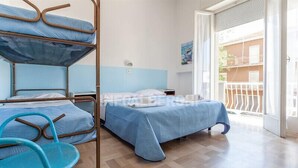 Une chambre de dortoir avec des lits superposés, un lit simple, une chaise et un balcon avec une rambarde.
