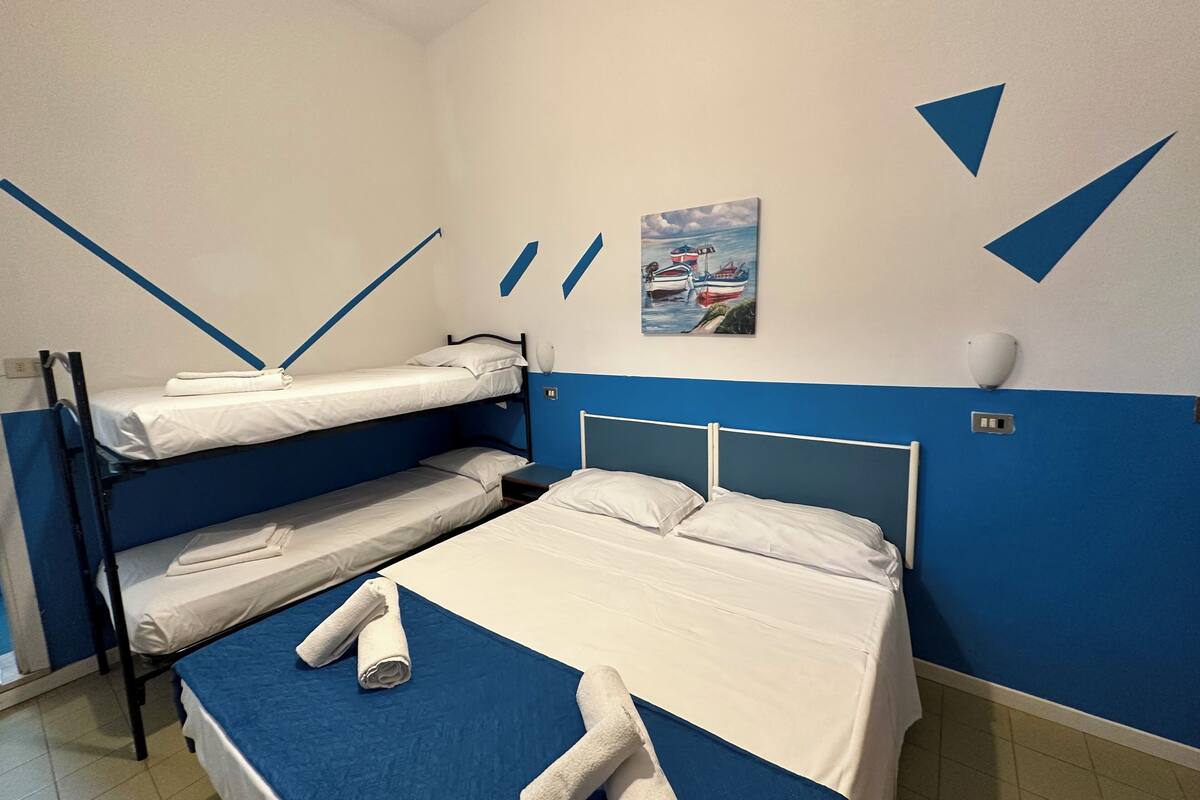 A room with bunk beds, a painting of boats, and blue and white walls.