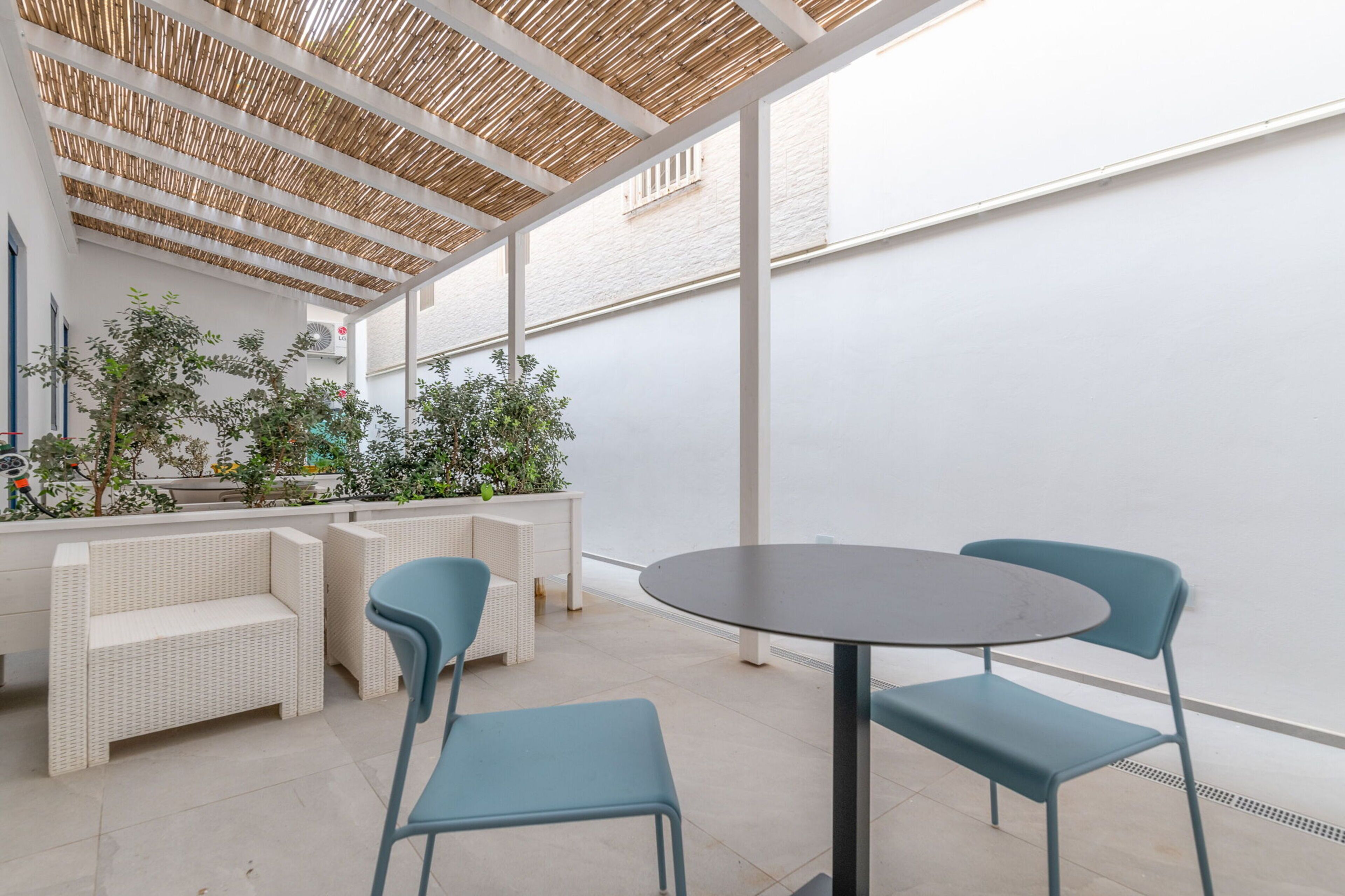 A covered outdoor seating area with wicker furniture and potted plants.