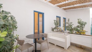 A modern interior with a round table and chairs, a white sofa, and potted plants.