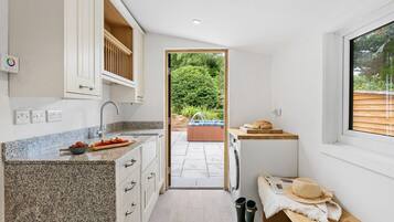 A compact kitchen with granite countertops, a built-in oven, and a view of a garden and hot tub outside.