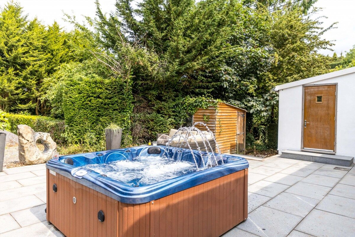 A hot tub outdoors with a wooden cabin in the background.
