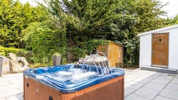 A hot tub outdoors with a wooden cabin in the background.