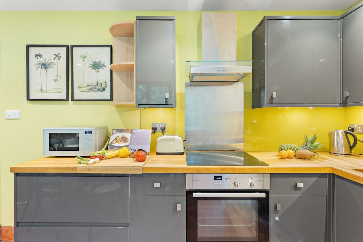 A modern kitchen with grey cabinets, a microwave, a toaster, and a stainless steel range hood.