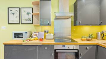 A modern kitchen with grey cabinets, a microwave, a toaster, and a stainless steel range hood.