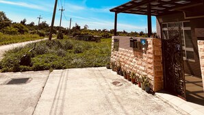 Zona residencial con camino de entrada pavimentado, muro de ladrillo y porche cubierto.