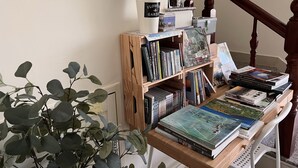 Una estantería de madera con libros y una pequeña planta en maceta.